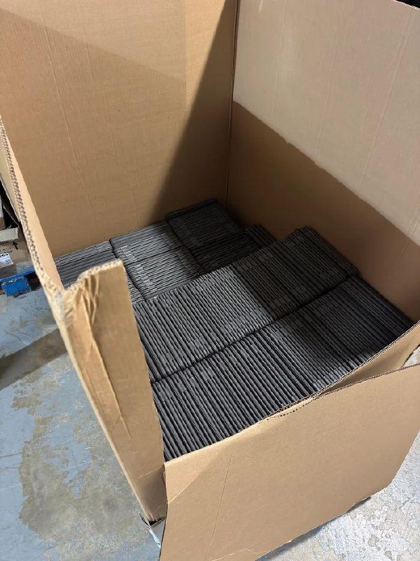 A tall cardboard gaylord box filled with stacks of retired Chromebooks, ready for pickup.