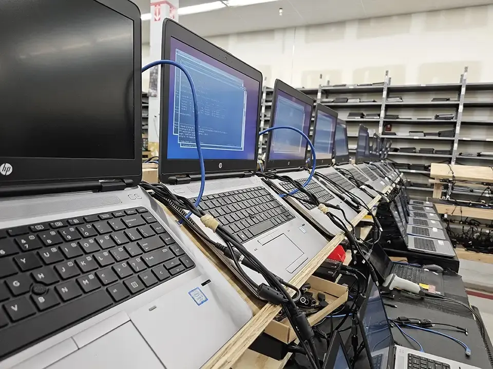 A row of laptops on a wiping bench, each connected by cable, with wipe screens running.